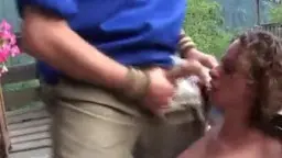 Frau mit Locken kniet, Schwanz im Mund auf Terrasse