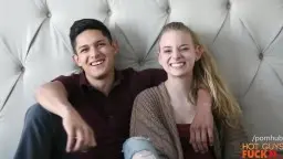 Junger Mann und blonde Teenagerin kuscheln lächelnd auf weißer Couch