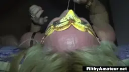 Blonde Frau liegt mit gelber Maske auf dem Gesicht und lässt sich vollpissen