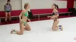 Ebony und blonde Wrestlerin knien sich gegenüber auf der weißen Matte in einem Ring